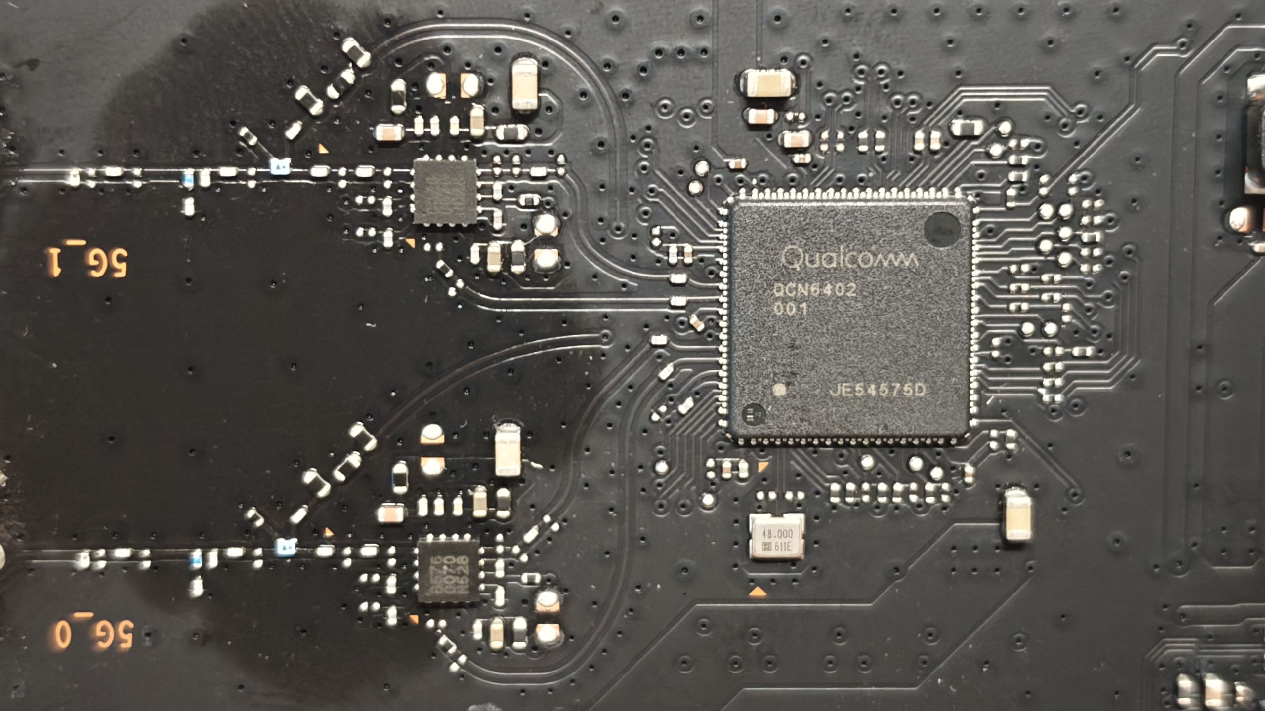 小米 BE3600 的 5G 射频芯片特写,丝印为 Qualcomm QCN6402 001,旁边是 48MHz 晶振