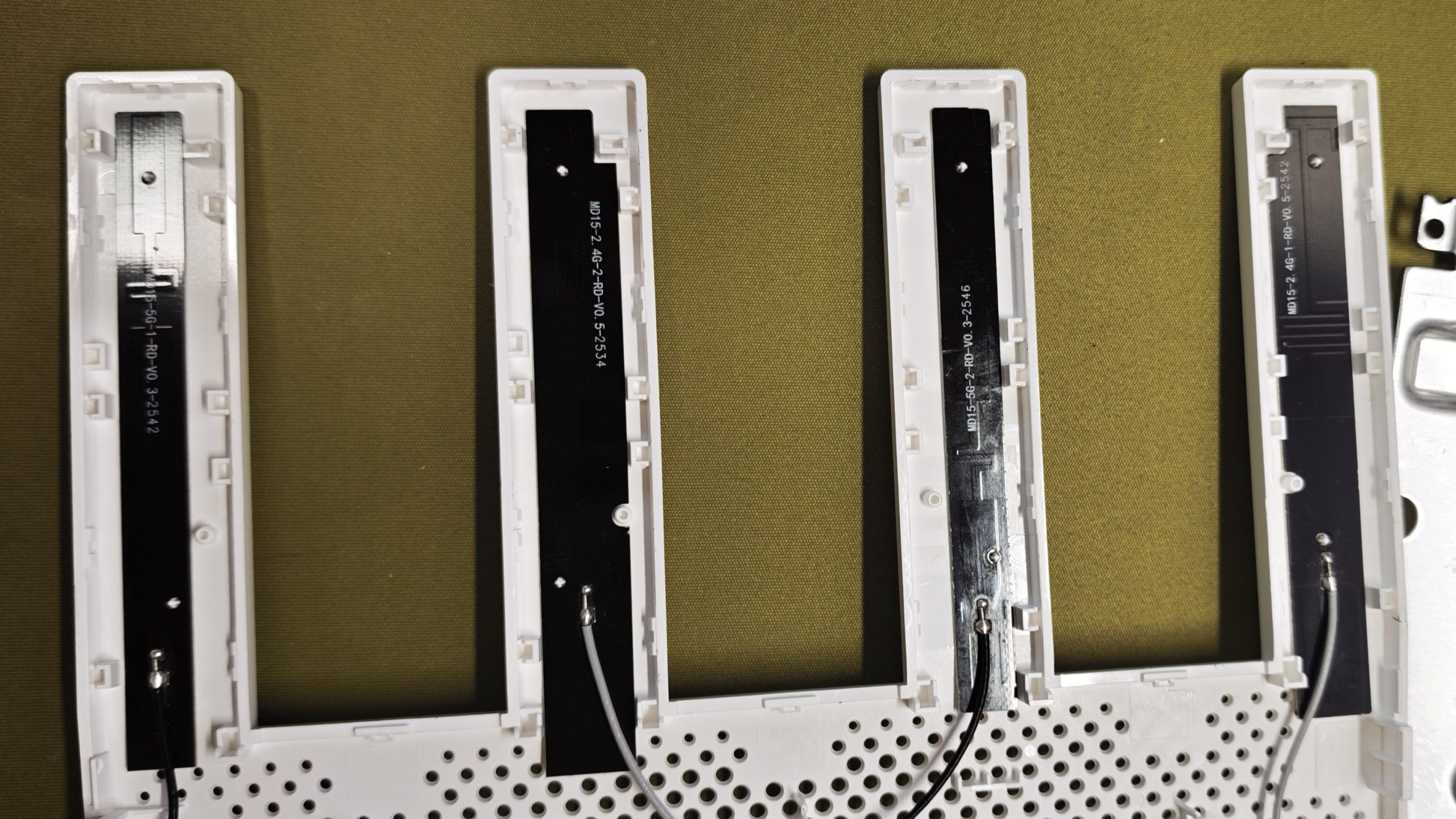 小米 BE3600 的四根天线并排展示,每根天线内部都是一片黑色 PCB 振子并标注了料号